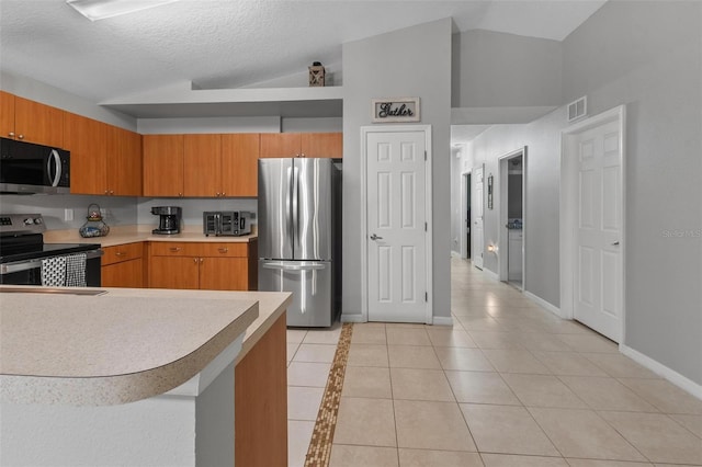 kitchen featuring visible vents, stainless steel appliances, light countertops, light tile patterned floors, and lofted ceiling