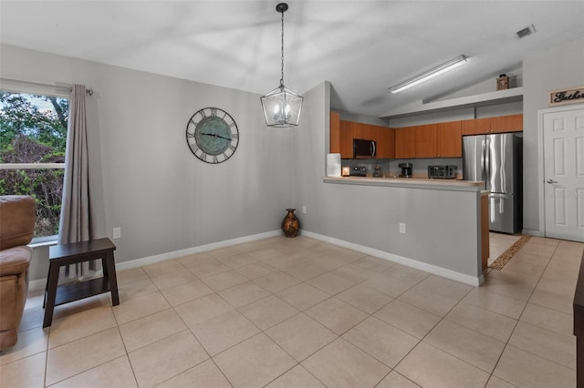 kitchen featuring light tile patterned floors, vaulted ceiling, light countertops, appliances with stainless steel finishes, and brown cabinets