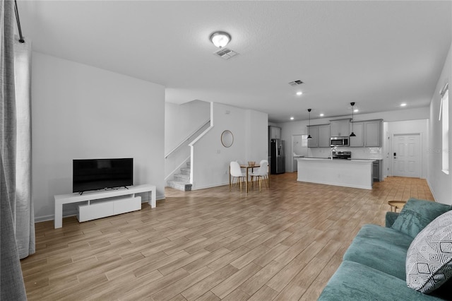 living room with light wood-type flooring, stairway, visible vents, and recessed lighting