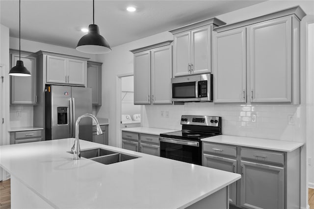 kitchen with decorative backsplash, gray cabinetry, stainless steel appliances, and a sink