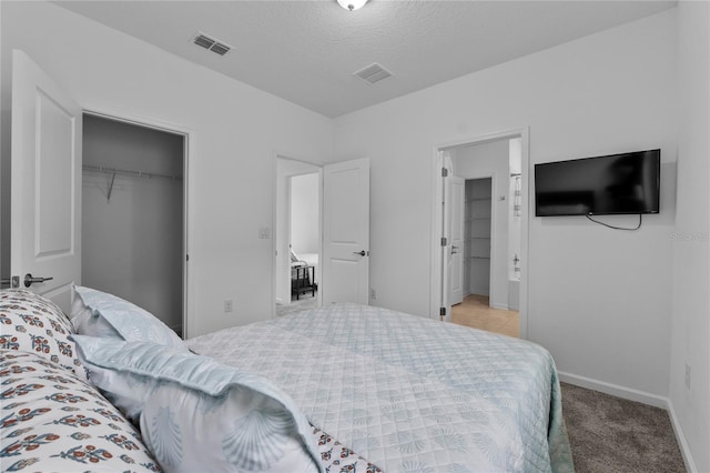 bedroom featuring visible vents, baseboards, a spacious closet, a closet, and light colored carpet