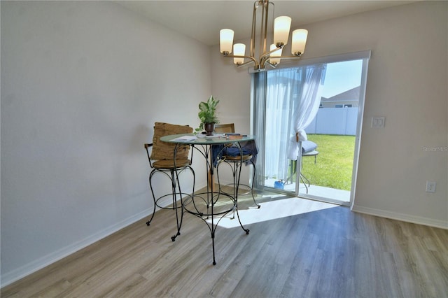 dining space with a chandelier, baseboards, and wood finished floors