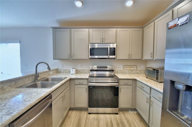 kitchen with gray cabinetry, a sink, recessed lighting, stainless steel appliances, and light wood finished floors