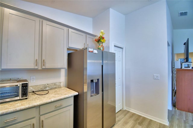 kitchen featuring visible vents, baseboards, light wood-type flooring, gray cabinets, and appliances with stainless steel finishes