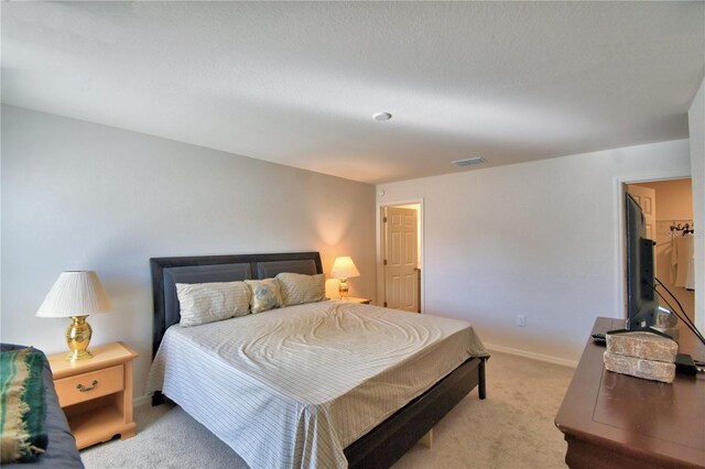 bedroom featuring visible vents, light carpet, and baseboards