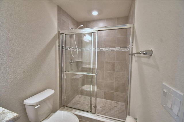 bathroom with a stall shower, toilet, and a textured wall