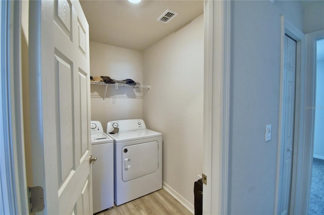 washroom featuring visible vents, light wood-type flooring, washer and dryer, baseboards, and laundry area