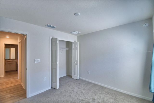 unfurnished bedroom featuring visible vents, baseboards, carpet, and a closet