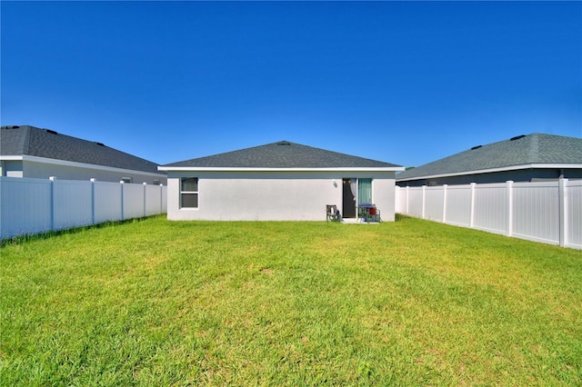 back of house featuring a yard, a fenced backyard, and stucco siding