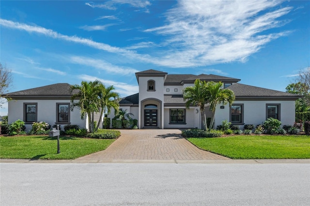 view of front facade with stucco siding, decorative driveway, and a front yard