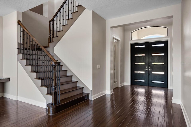 entryway featuring baseboards, a textured ceiling, wood finished floors, and stairs