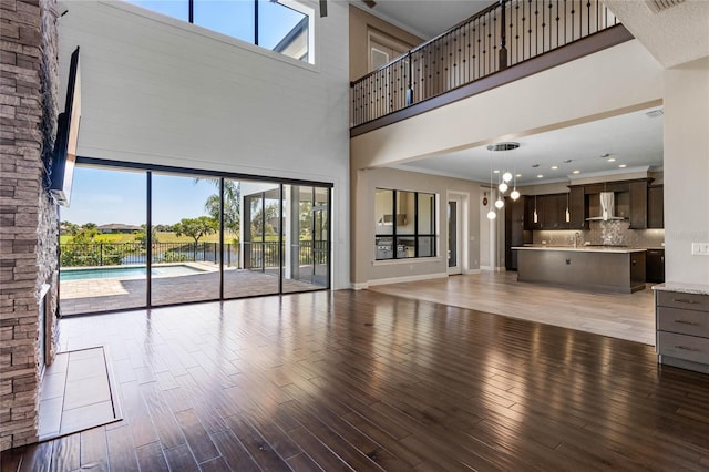 unfurnished living room with light wood-style flooring, a high ceiling, and baseboards