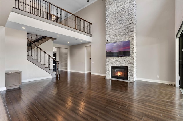 unfurnished living room with stairway, a fireplace, baseboards, and wood finished floors