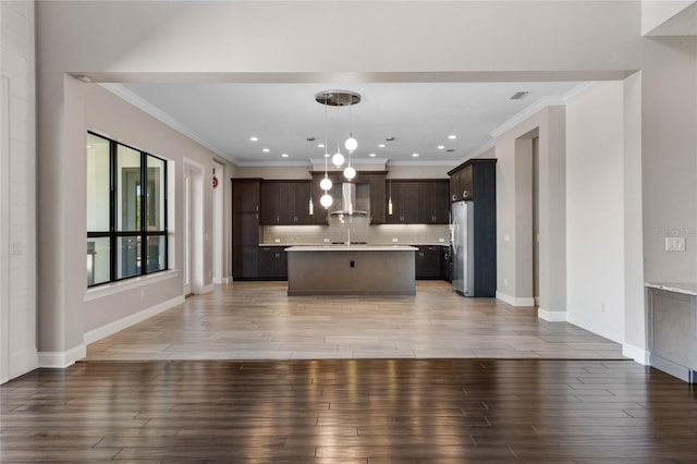 kitchen featuring dark brown cabinets, light countertops, freestanding refrigerator, and exhaust hood