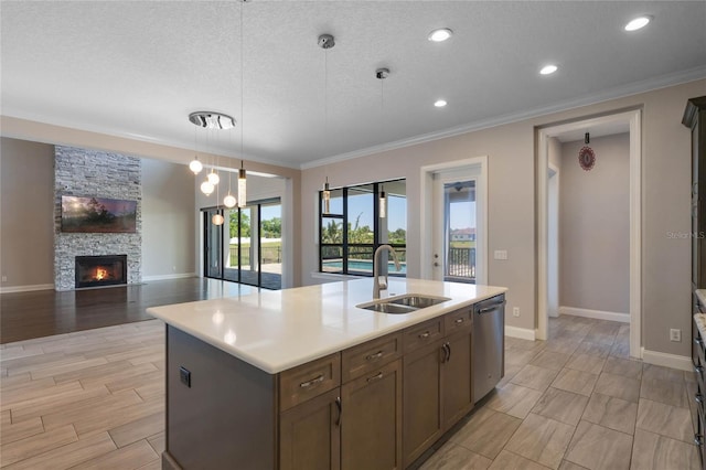 kitchen featuring a sink, open floor plan, an island with sink, ornamental molding, and stainless steel dishwasher