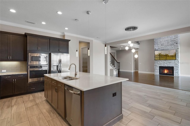 kitchen with a sink, appliances with stainless steel finishes, open floor plan, and light countertops