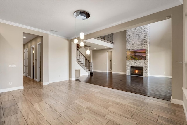 unfurnished living room with crown molding, baseboards, wood tiled floor, stairs, and a fireplace