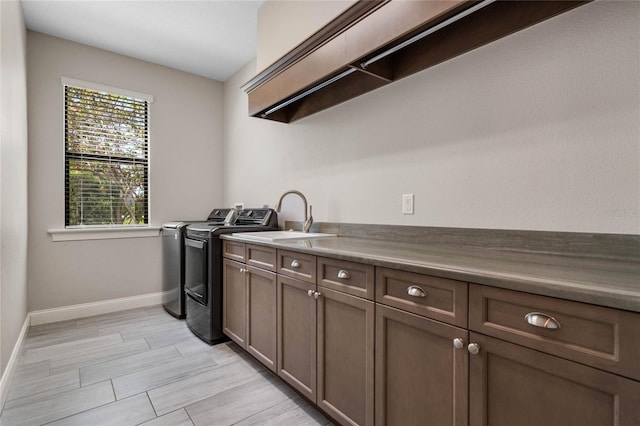 laundry area with a sink, baseboards, cabinet space, and washing machine and clothes dryer