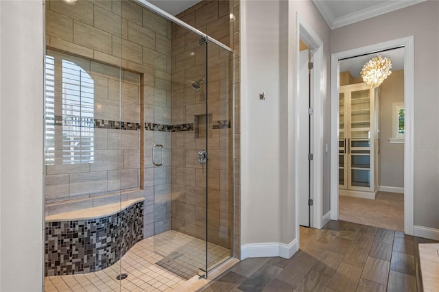 full bathroom featuring a shower stall, a notable chandelier, baseboards, and ornamental molding