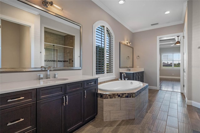 full bath with two vanities, a sink, a shower stall, crown molding, and a bath