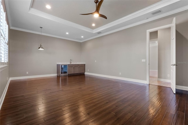 unfurnished living room with visible vents, dark wood-type flooring, beverage cooler, a raised ceiling, and a ceiling fan