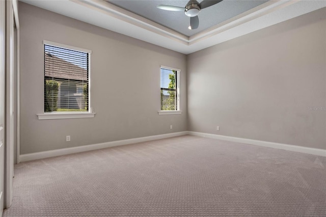 unfurnished room featuring a raised ceiling, a ceiling fan, baseboards, and carpet floors