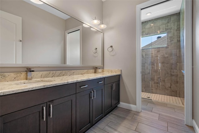 full bath with double vanity, walk in shower, and a sink