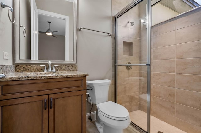 full bath featuring a ceiling fan, vanity, toilet, and a shower stall