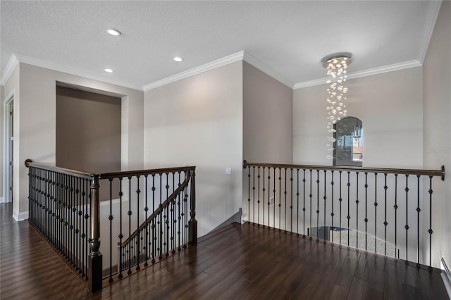 hall with an upstairs landing, ornamental molding, a textured ceiling, and wood finished floors