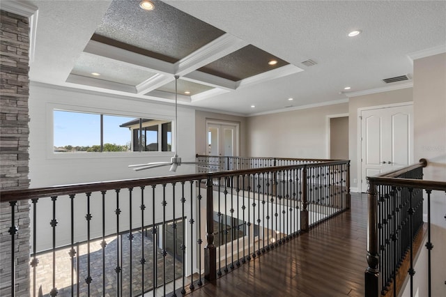 corridor featuring visible vents, coffered ceiling, a textured ceiling, wood finished floors, and crown molding