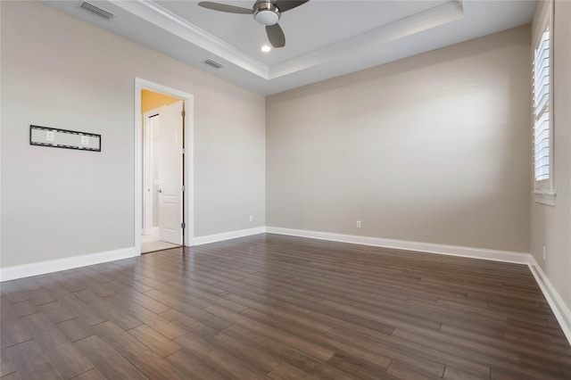 spare room featuring ceiling fan, visible vents, a raised ceiling, and dark wood finished floors