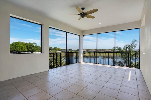 unfurnished sunroom with a ceiling fan and a water view