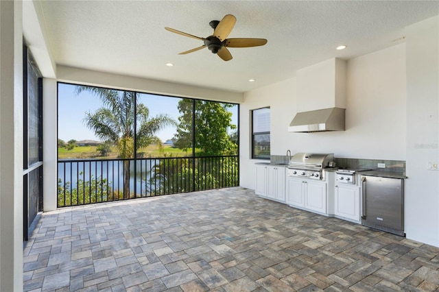 exterior space featuring grilling area, a water view, an outdoor kitchen, and a ceiling fan