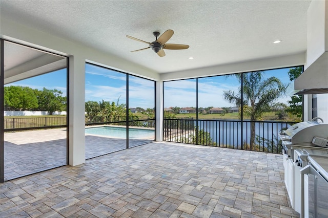 unfurnished sunroom featuring a wealth of natural light, a water view, and ceiling fan