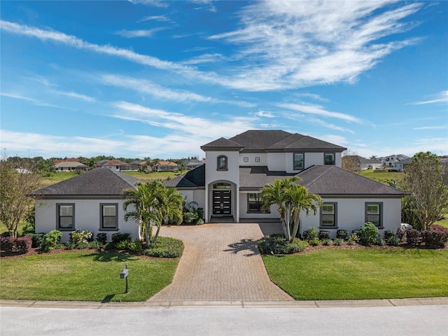 view of front facade featuring stucco siding, decorative driveway, and a front lawn