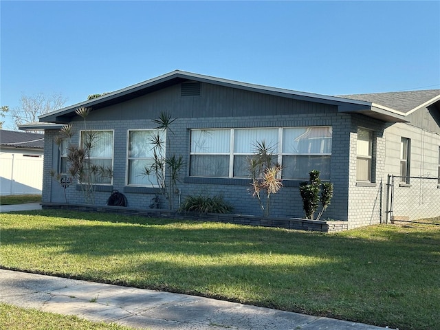 view of side of home with brick siding, a lawn, and fence