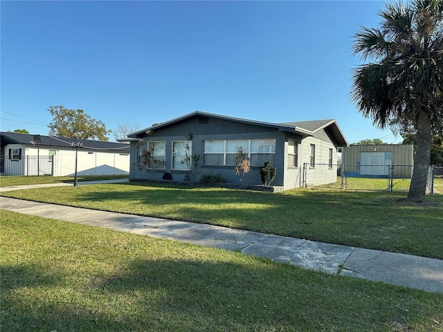 view of front of house with a gate, brick siding, a front lawn, and fence