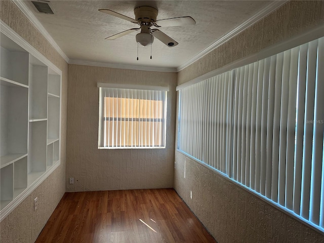 unfurnished room with a textured ceiling, wood finished floors, ceiling fan, and ornamental molding