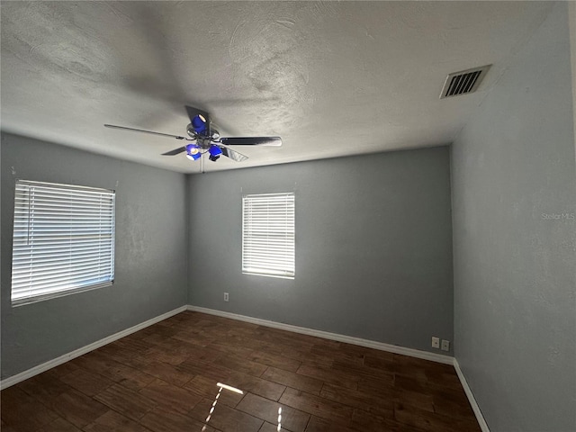 spare room featuring a ceiling fan, wood finished floors, visible vents, and baseboards