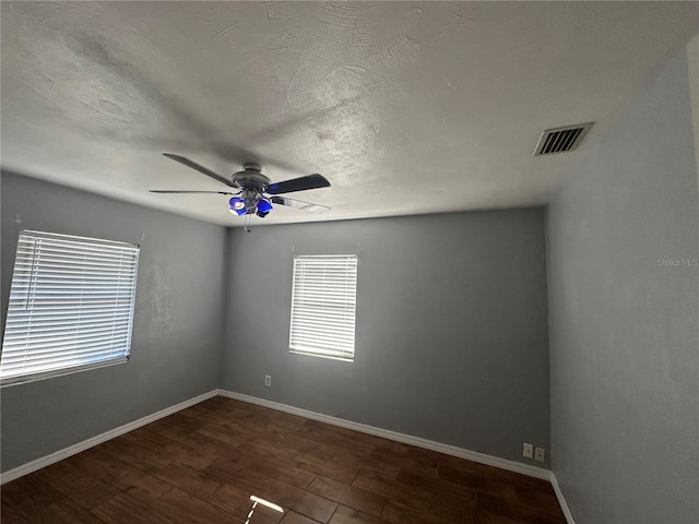 empty room featuring visible vents, baseboards, a textured ceiling, and wood finished floors