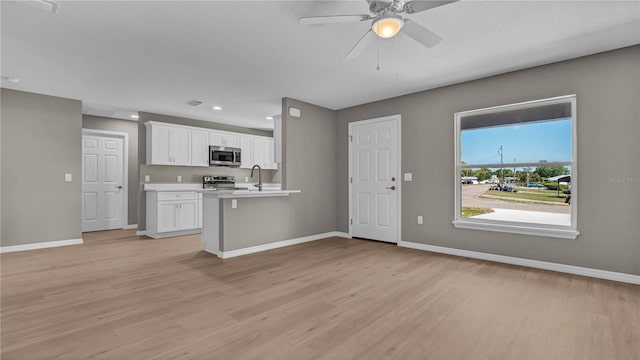 kitchen featuring baseboards, light countertops, light wood-style floors, white cabinets, and stainless steel appliances