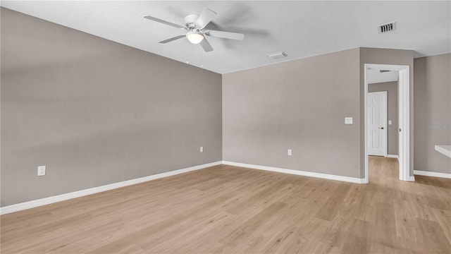 empty room with visible vents, light wood-style flooring, baseboards, and ceiling fan