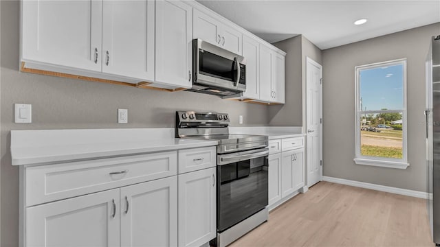 kitchen featuring baseboards, light wood-type flooring, light countertops, appliances with stainless steel finishes, and white cabinetry