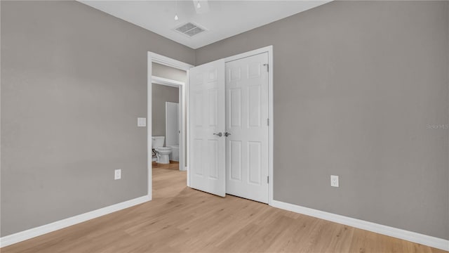 unfurnished bedroom with a closet, visible vents, light wood-style flooring, and baseboards