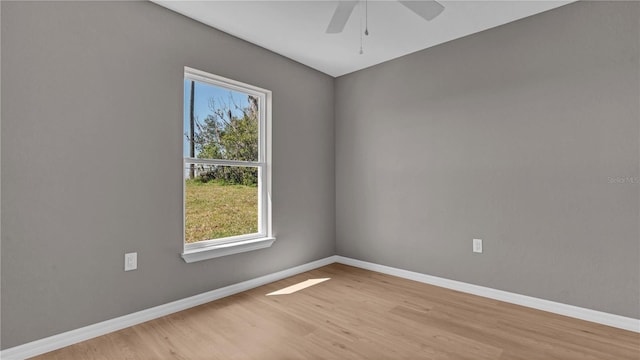 spare room featuring ceiling fan, light wood-type flooring, and baseboards