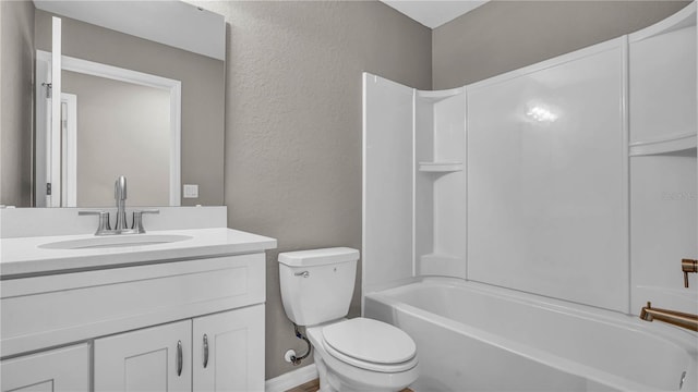 full bath featuring baseboards, toilet, bathing tub / shower combination, a textured wall, and vanity