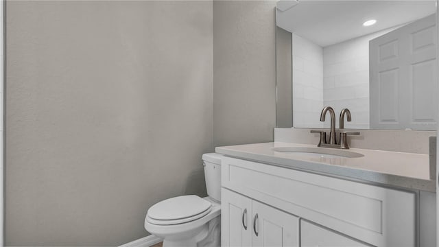 bathroom with baseboards, toilet, and vanity