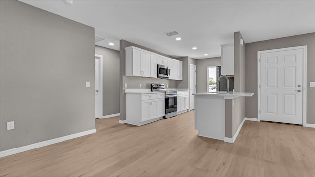 kitchen featuring visible vents, light countertops, a peninsula, light wood-style floors, and stainless steel appliances