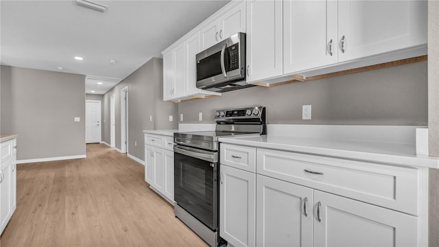 kitchen with light wood-type flooring, visible vents, stainless steel appliances, white cabinets, and light countertops