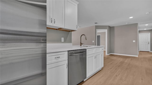 kitchen with a sink, light countertops, white cabinets, light wood-style floors, and appliances with stainless steel finishes